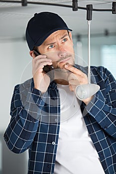 certified electrician checking information about burned out light bulb