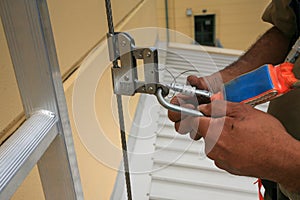 Certified industrial worker inspecting locking Karabiner which connecting with fall arrest shock absorbing safety lanyard