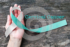 Cervical Cancer awareness with Teal and white ribbon symbolic bow color on woman helping hand support