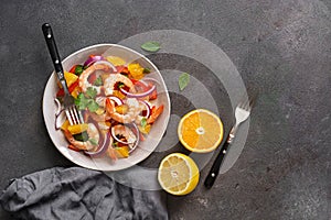 Ceviche salad with shrimps and oranges on a dark rustic background. Latin American food. Top view, flat lay, copy space