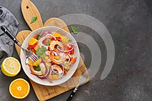 Ceviche salad with shrimps and oranges on a dark rustic background. Latin American food. Top view, flat lay, copy space