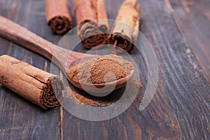 Ceylon cinnamon sticks and powder in the spoon on a wooden background