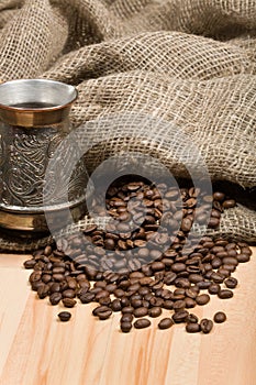 Cezve with freshly roasted coffee beans on table
