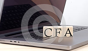 CFA word on wooden block on laptop, business concept