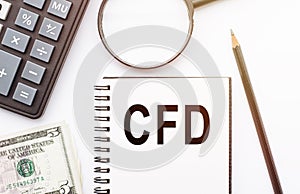 CFD Contract For Difference acronym written on notepad next to calculator, pencil, magnifier and money on white table. business