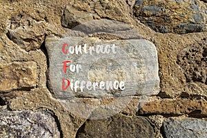 CFD symbol. Concept words CFD contract of difference on beautiful big stone in stone wall. Beautiful stone wall background.