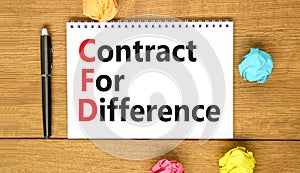 CFD symbol. Concept words CFD contract of difference on beautiful white note. Beautiful wooden table wooden background. Business