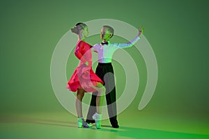 Cha cha cha, rumba, tango. Carming little boy and beautiful girl dancing ballroom dance isolated over green background