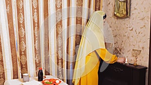 A Chabad Jewish woman in a wig and a head covering on the eve of Pesach, which coincides with Saturday, lights candles.