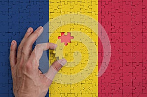 Chad flag is depicted on a puzzle, which the man`s hand completes to fold
