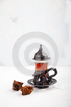 Chaga tea in a Turkish glass on a light background. Healthy food concept. Copy spaes
