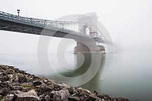 Chain Bridge over the Danube and a boat, Budapest, Hungary, in fog, evening lights