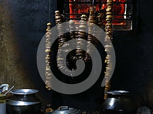 Chain of cut brindle berry or Malabar tamarind hung for drying at fire place in a village home photo