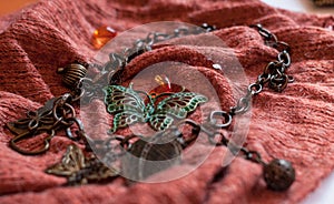 Chain with decorative leaves, beads, butterflies on red cloch