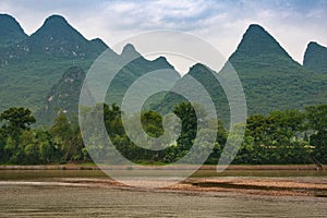 Chain of forested Karst mountains and marsh land in front along Li River in Guilin, China