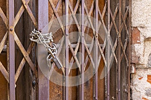 A chain is hanging from a rusty gate