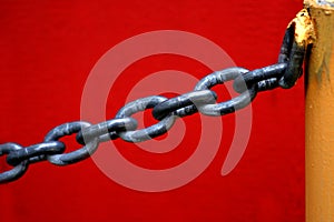 Chain Hanging from Yellow Pole with Red Wall Background
