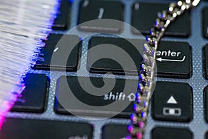 Chain on laptop computer keyboard, glowing optical fibres