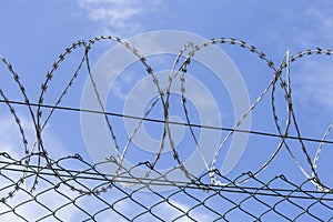 Chain link fence with barbed wire under blue sky