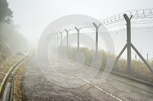 Chain-link fencing and Barbed wire in Fog