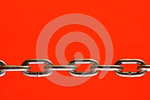 A chain of links is isolated on a red background.