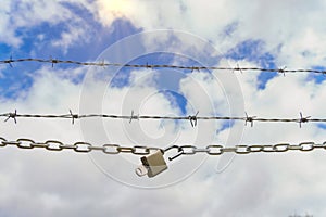 chain with padlock open with key next to a barbed wire