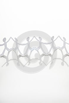 Chain of paper men holding hands on white background, vertical shot