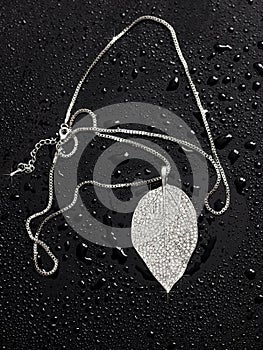 Chain with a pendant in drops of water on a black background