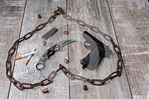 A chain, pistol, cartridges, a knife and cigarettes with a black lighter.