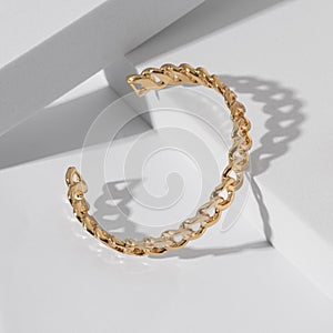 Chain shape golden cuff bracelet on geometric white background with copy space