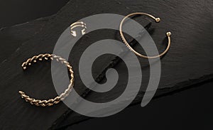 Chain shape and golden with diamonds bracelets and ring on dark stone plates with copy space