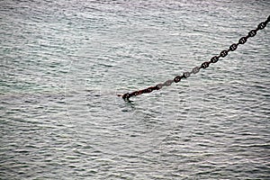The chain from the ship`s anchor going into the depths of the sea