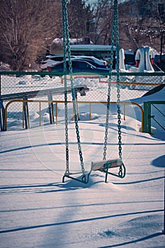 Chain swing is covered with snow.