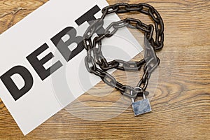 Chain with word DEBT. Concept of debt and financial entrapment.