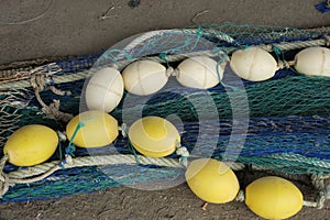 Chain of yellow and white floaters laying on a blue green fishingnet