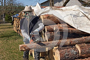 Chainsaw in action cutting wood. Man, cutting wood with saw,wearing a protection face mask, in coronavirus COVID-19