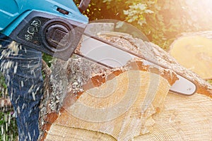 Chainsaw. Chainsaw in move cutting wood. Man cutting wood with saw. Dust and movements. Close-up of woodcutter sawing chain saw.