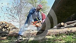 Chainsawing wood in slow motion shot from under log