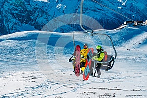 Chair cable lift with snowboarders in winter sunny day