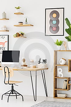 Chair at desk with desktop computer in bright workspace interior