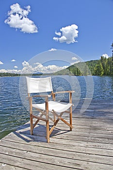 A chair on the dock of a beautiful lake