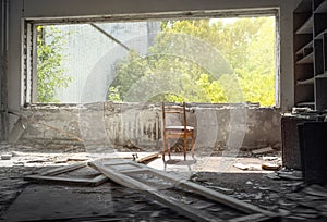 Chair near the window in destroyed room of abandoned building in Pripyat,