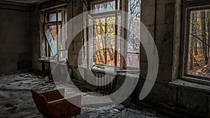 Chair opposite the window in the room of an old ruined abandoned house in Pripyat in Ukraine