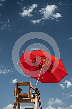 Chair and red SOS umbrella of a lifeguard in a beach
