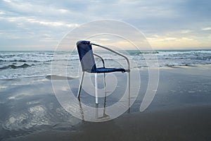 The chair stands on the beach in the water. Rest without tourists.