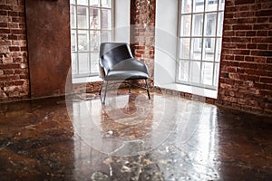 Chair stands near a window on the brick wall background in the w