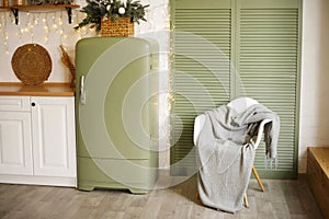 Chair with warm blanket and green refrigerator in Christmas interior in the kitchen
