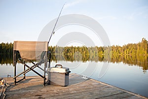 A Chair on a Wooden Dock Looking Out on a Lake in Summer with Fishing Equipment