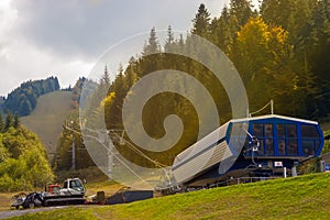 Chairlift bottom base and snow plow bulldozers in a warm sunbeam mountain scene