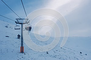 Chairlift that climbs the high mountain of the Pyrenees on a cloudy and snowy day with fog in Andorra, Grandvalira.